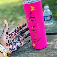 a hand with a painted hand holding a pink tumbler