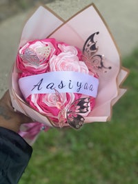 a person holding a bouquet of pink flowers with the word yaya written on it