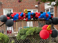 a red, blue, and black balloon arch on a porch