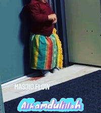 a child in a colorful skirt standing next to a door