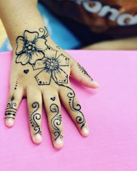 a child's hand with henna tattoos on it