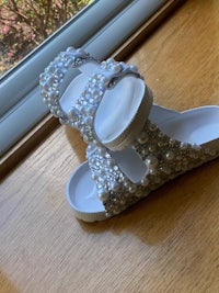 a pair of white sandals with pearls on them