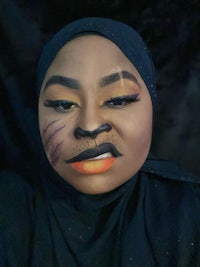 a woman wearing a black hijab with a cat face makeup